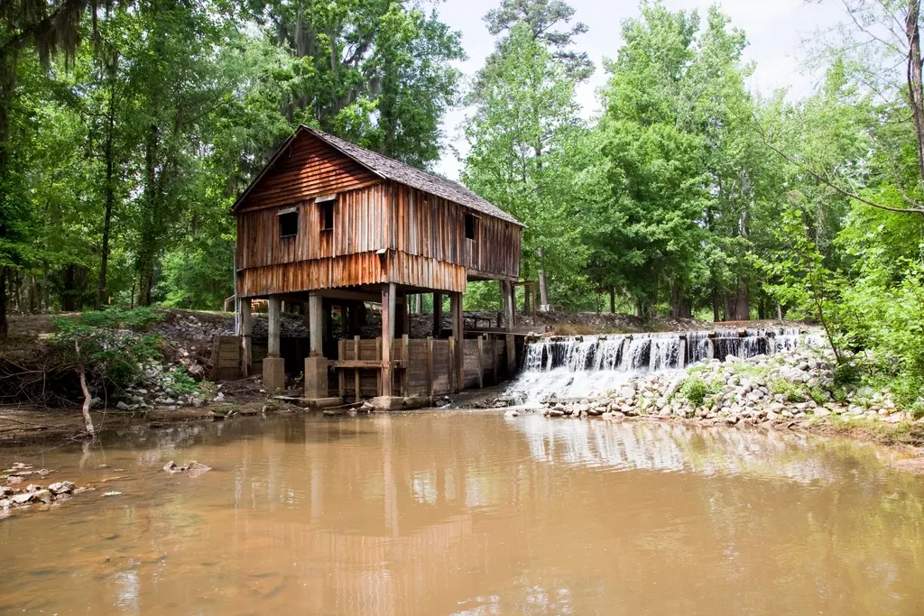 Moulin en bois au bord de l'eau, entouré d'arbres