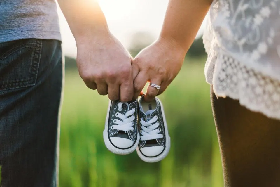 Chaussures de bébé tenues par ses parents en plein air